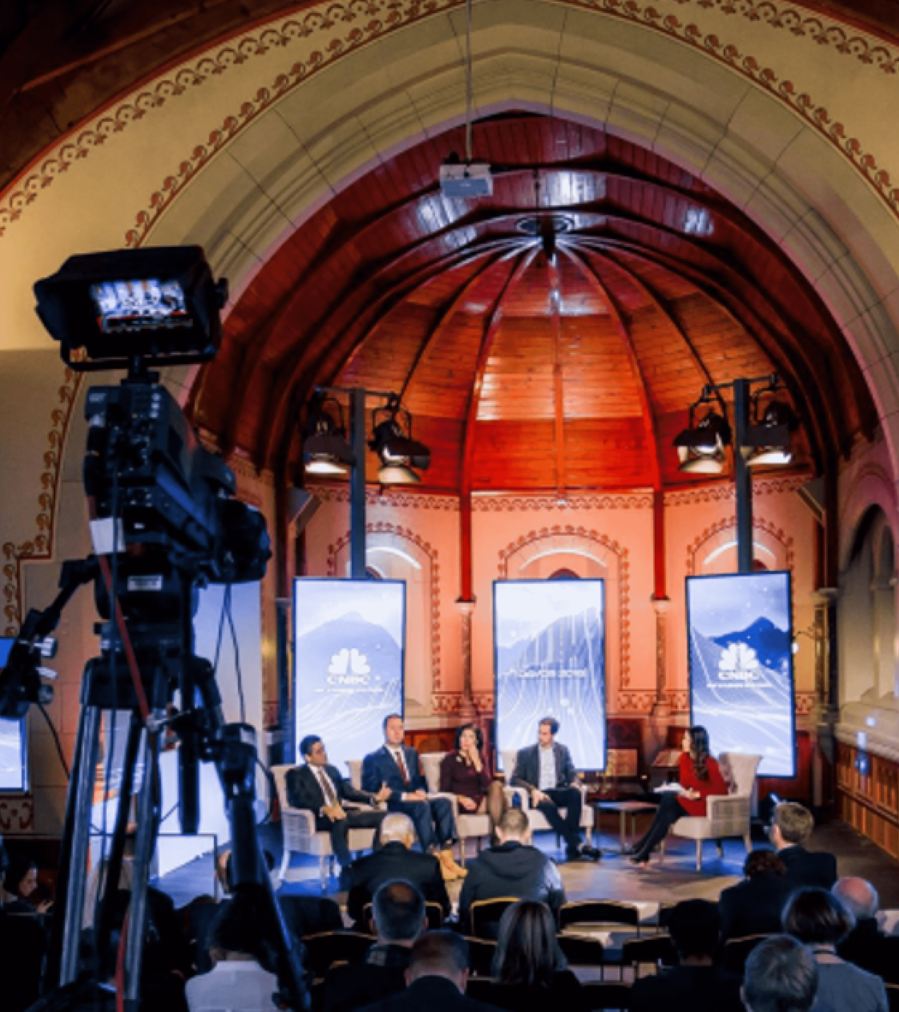A group giving a talk at Davos with a camera in view. 